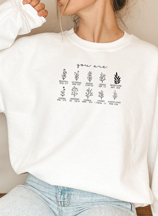 White sweatshirt with printed text and graphics worn by a person