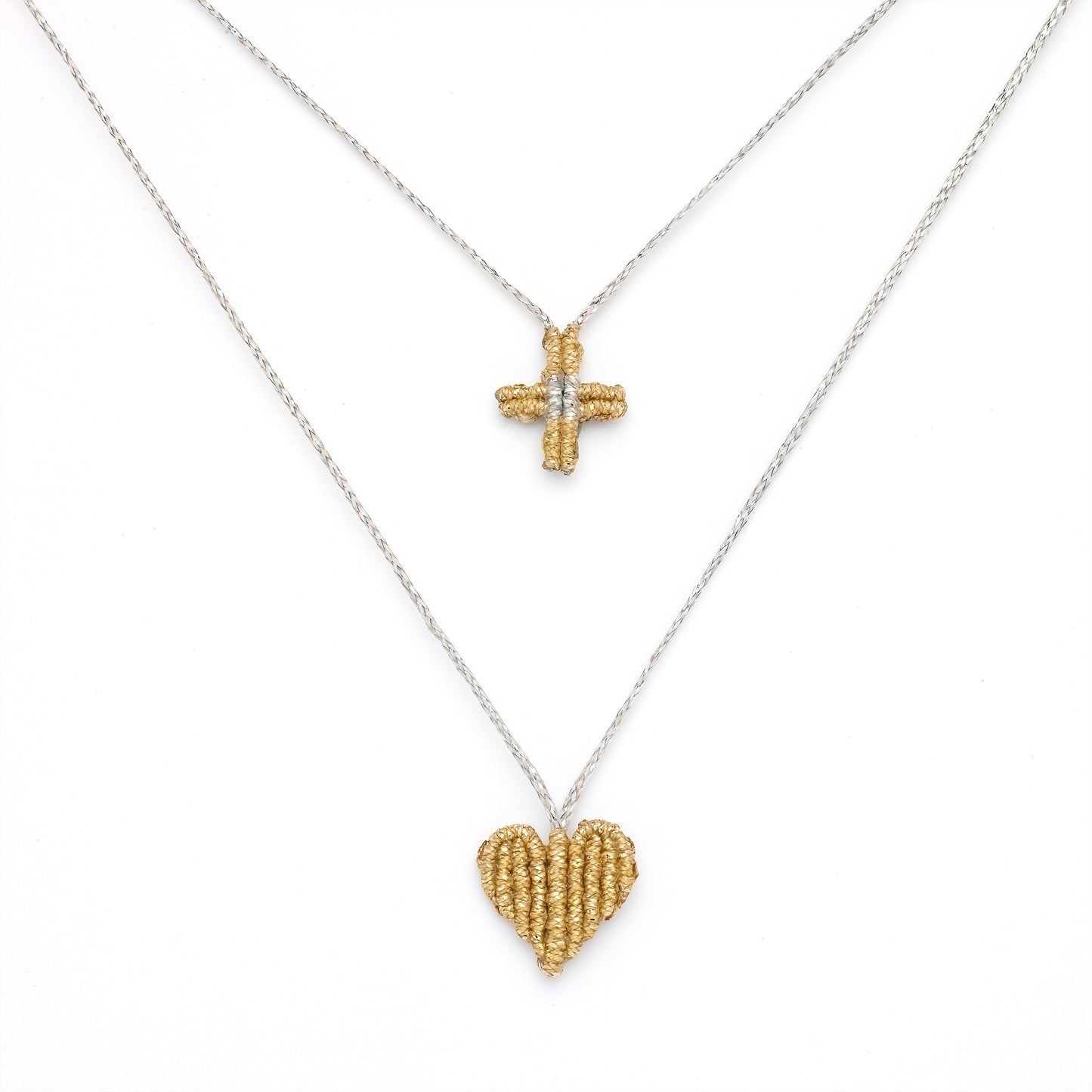 Gold heart and cross pendant on a silver chain against a white background