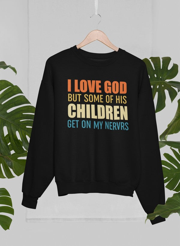 Black sweatshirt with colorful text on a hanger against a white wall with green leaf patterns.