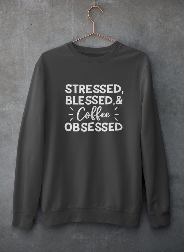 Dark gray sweatshirt with 'Stressed, Blessed & Coffee Obsessed' text on a gray background