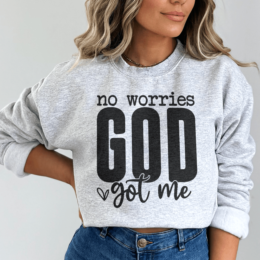 Person wearing a gray sweatshirt with 'no worries GOD got me' text on a plain background